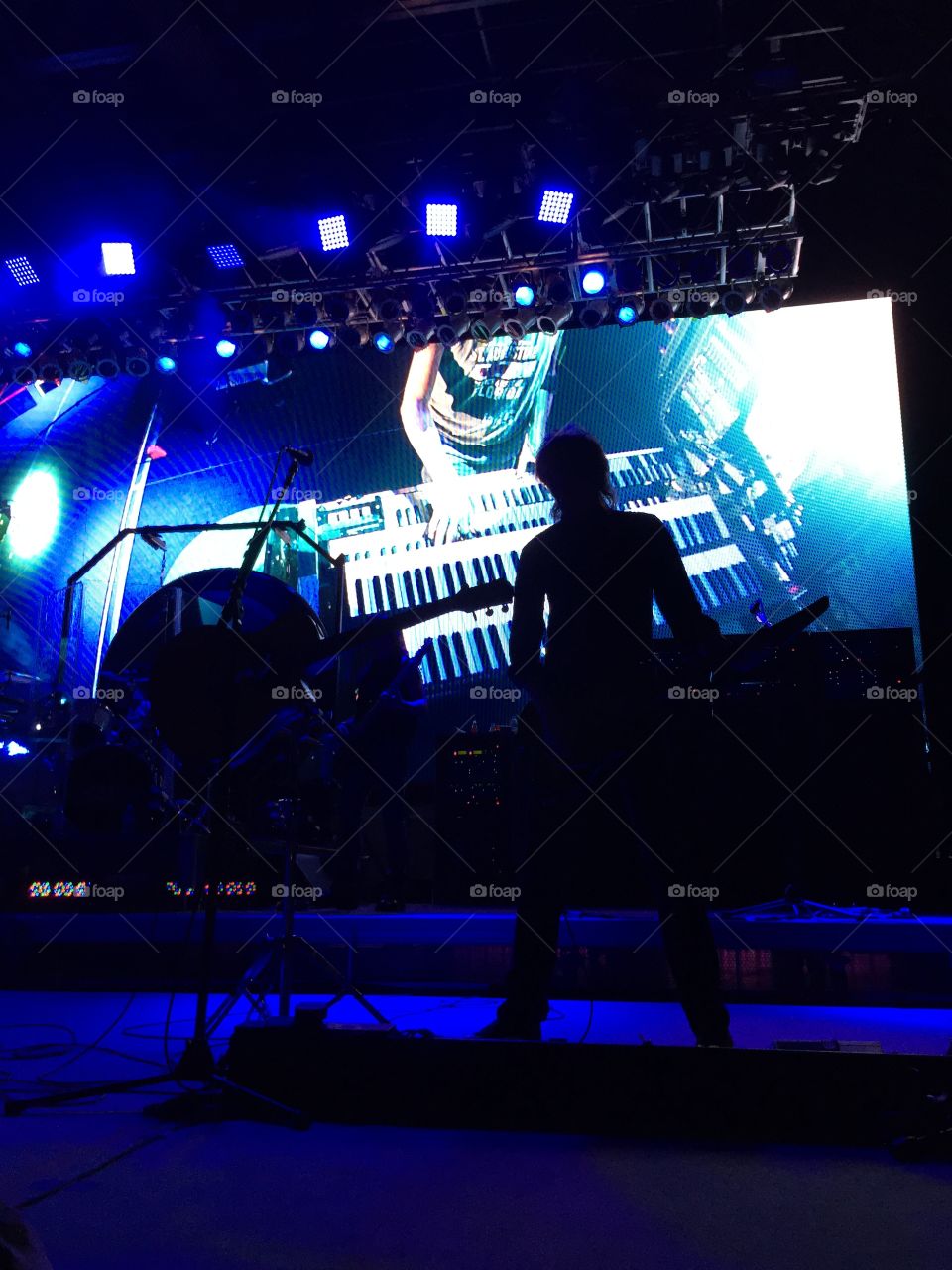 A performer on stage is silhouetted against an LED screen.