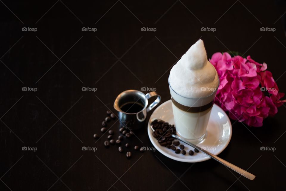 Topview of latte macchiato with coffee beans on wodden café table