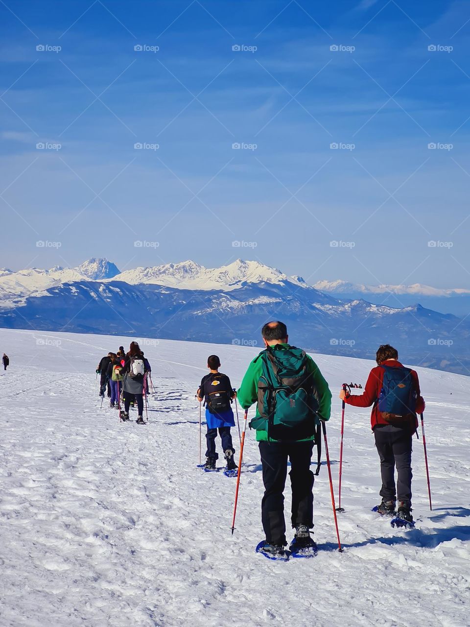 group of sportsmen walks on the snowy mountain with snowshoes