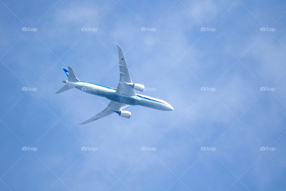 A portrait of a touristic airplane flaying through a blue sky with tin clouds. the aircraft is carrying tourists to and from a holiday location during summertime
