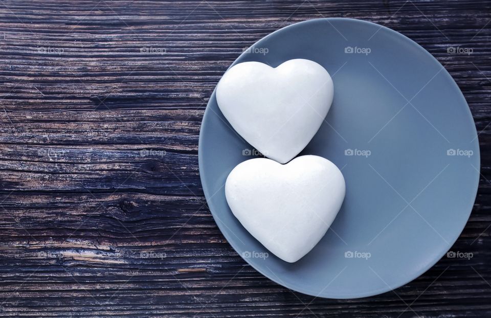 White gingerbread in the shape of hearts on a gray plate on a wooden table