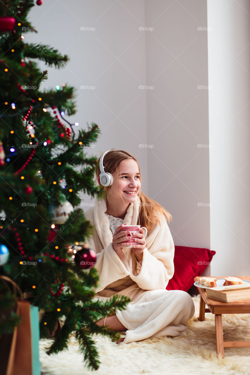 Happy woman sitting on carpet enjoying cup of coffee