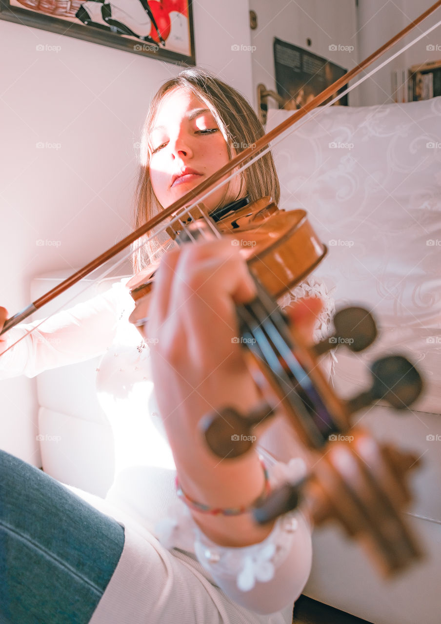 Girl holding a violin in the house