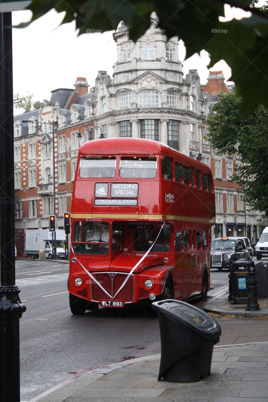 A beautiful red double decker bus traveling with a wedding party down the Streets in London 