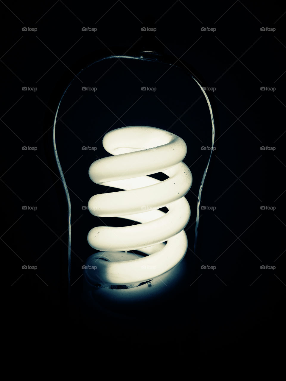 Spiral light bulb illuminated and isolated in the dark, black background, concept energy, idea, creativity, hope, direction, breakthrough, problem solving, solutions