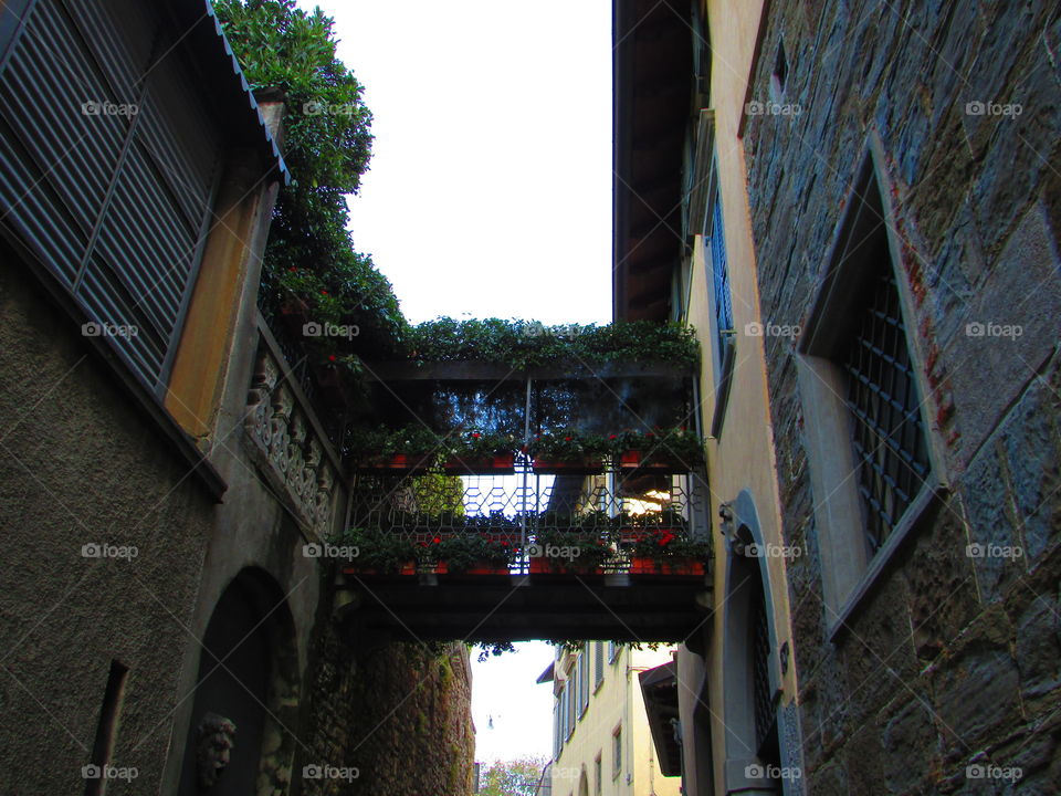 These two buildings are connected with a small bridge full of flowers in Bergamo Italy