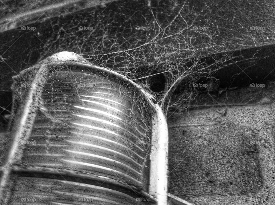 Close up of cobwebs on a lamp in black and white.