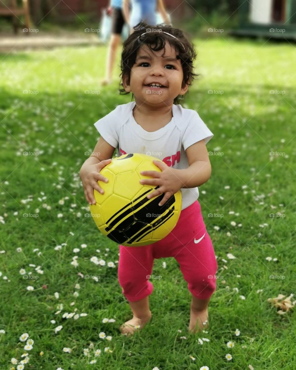 Happy running baby girl with football