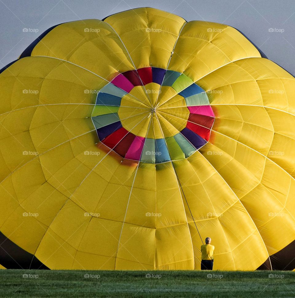 Man in yellow dwarfed by yellow balloon