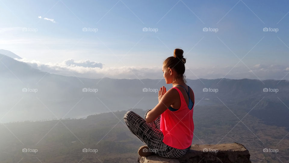 Young girl meditates at th top of the mountain at sunrise