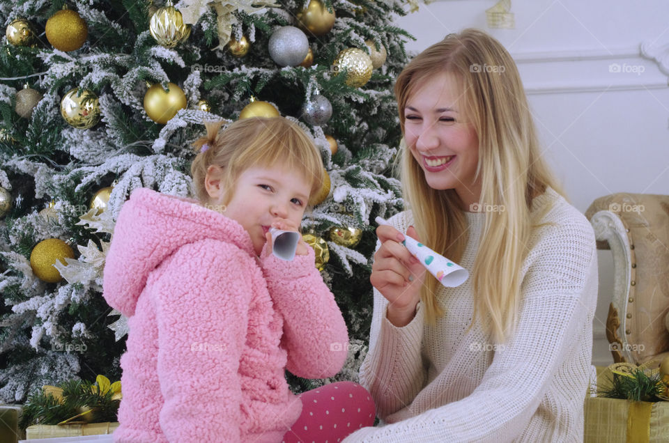 mom and daughter laugh near the Christmas tree