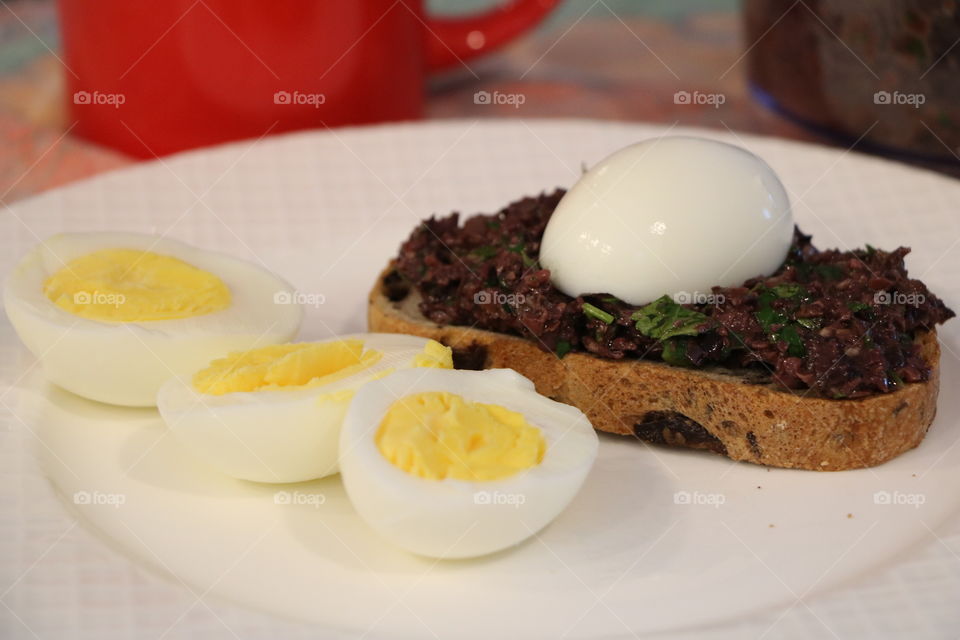 Olive tapenade on toasted bread and egg on top of it