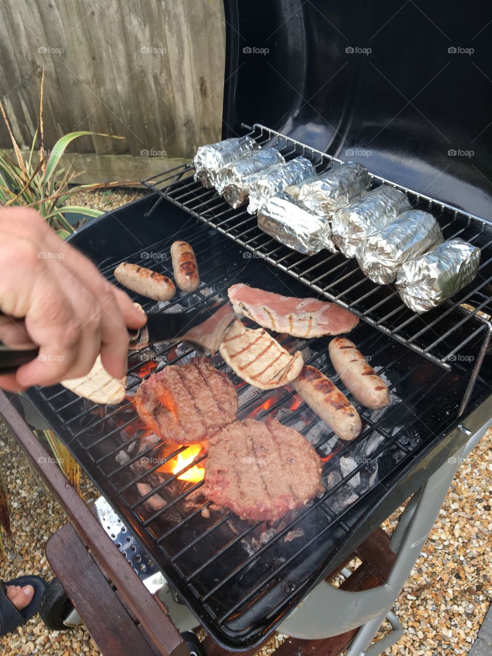 A man turns meat on a family barbecue or bbq