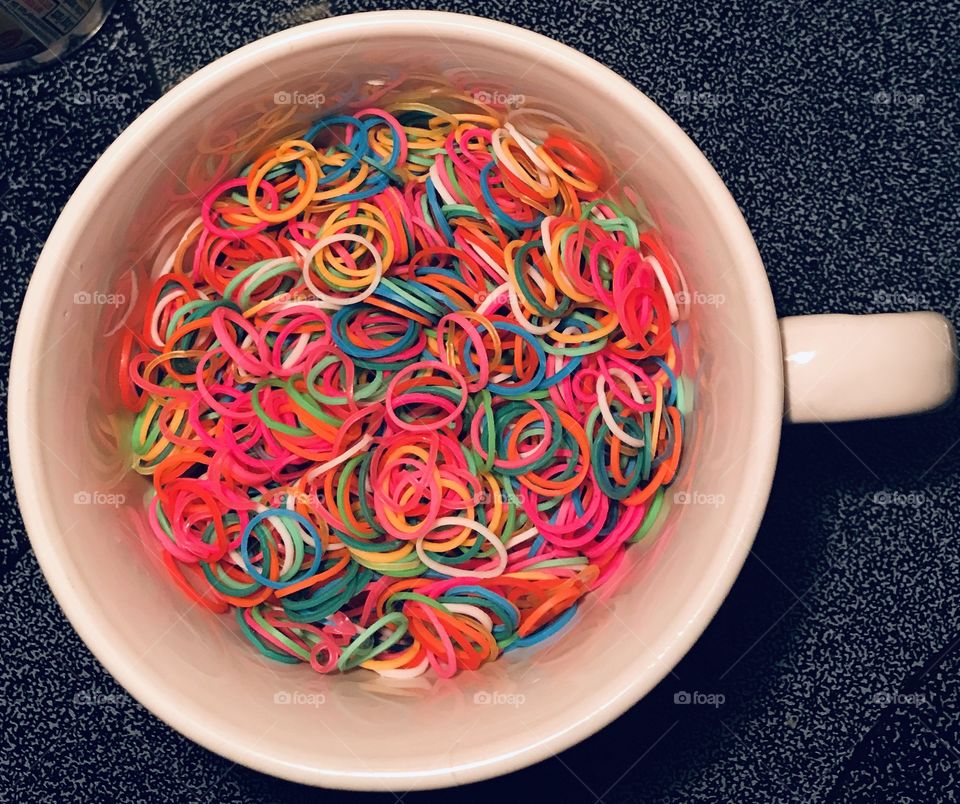 A colorful blend of rubber band circles resting inside the circle of a cup from the woods of South Georgia. 