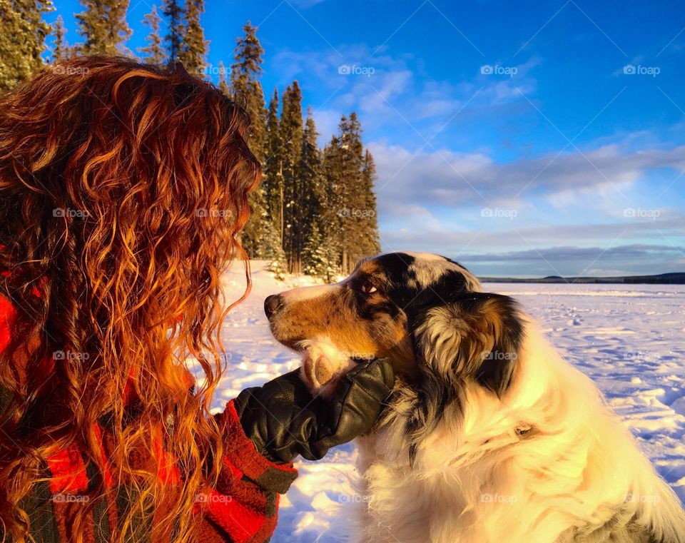 A girl holding hands with her dog. Off Grid living in a winter wilderness. Canadian scene, buffalo plaid and curly red hair. 
