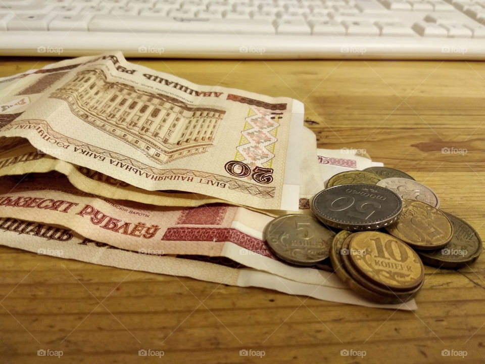 Banknotes and coins lying next to keyboard