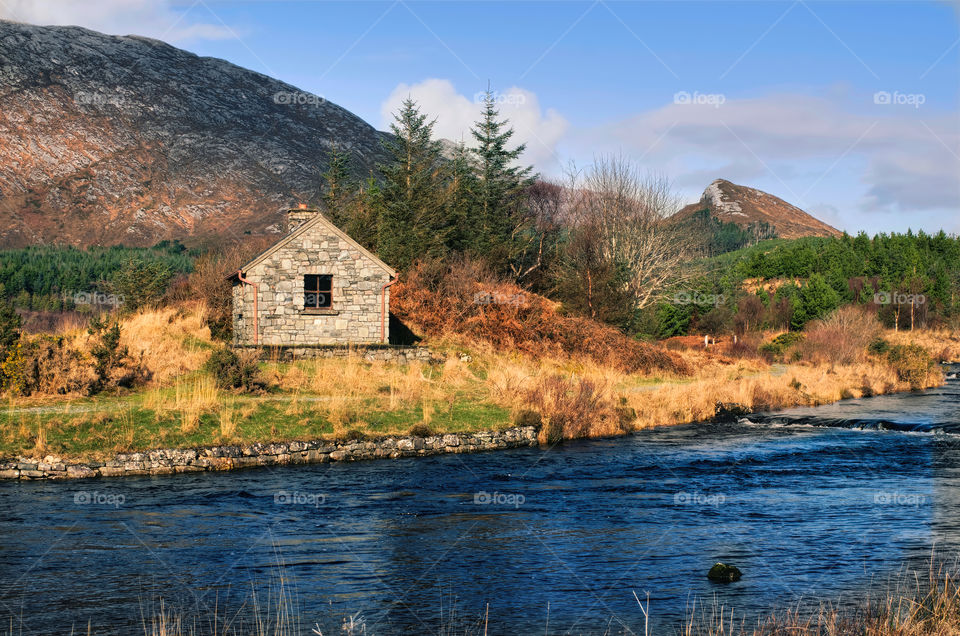 Stone house by the river surrounded with mountains at Derryclare natural reserve in Connemara National park, county Galway, Ireland