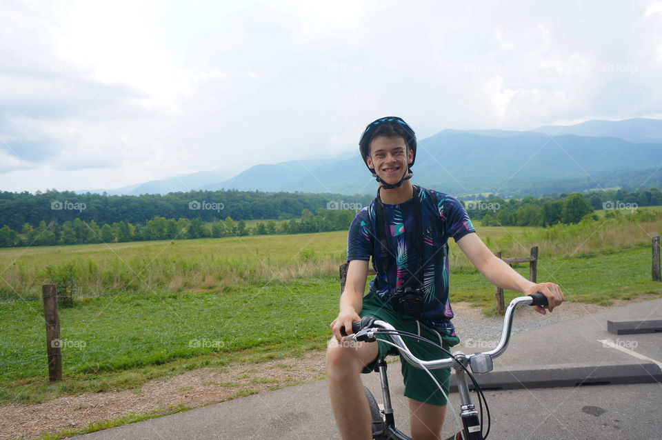 Boy smiling on a bike with mountains in the background
