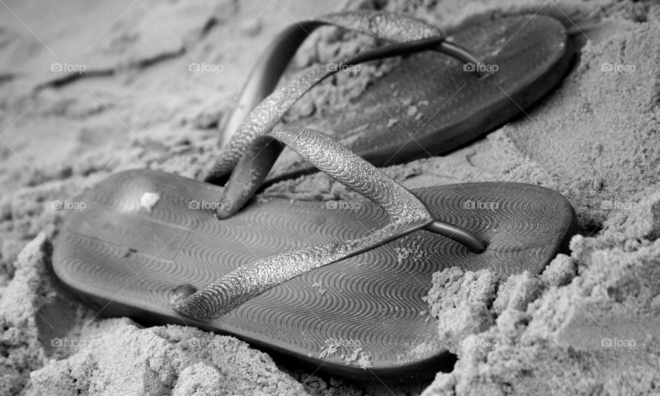 Silver flip flops on the beach sand