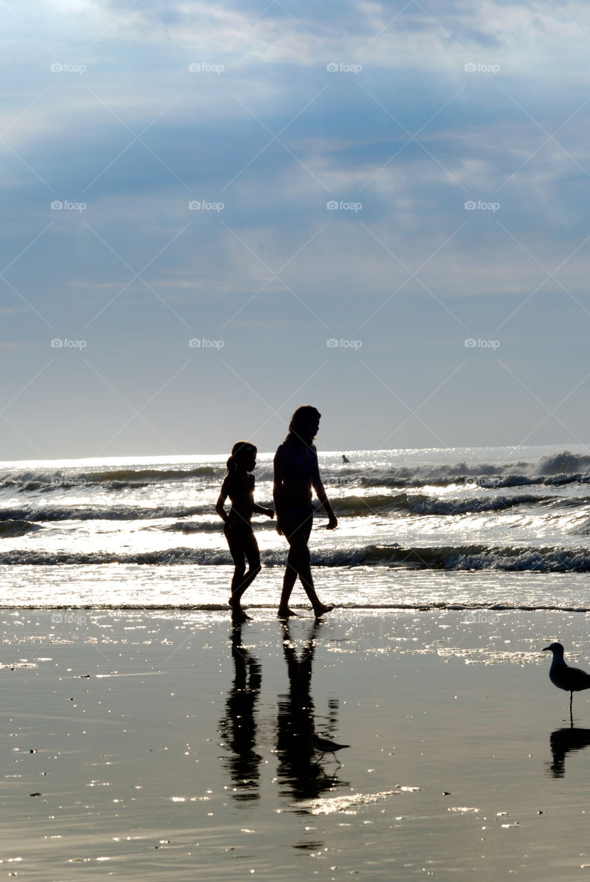 Silhouette of Mom and Daughter Walking on the Beach