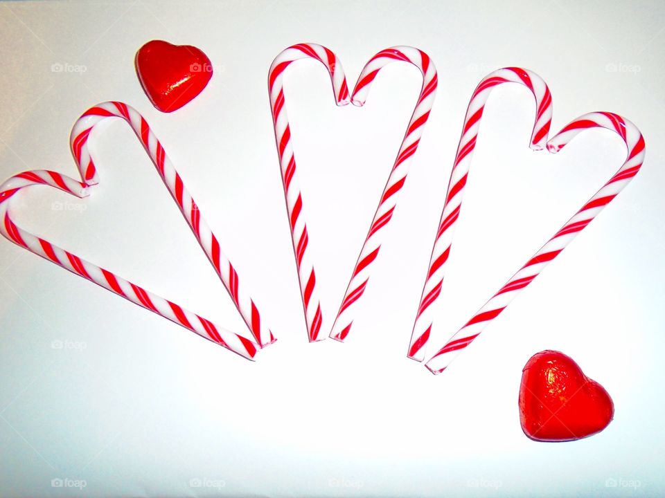 Hearts made of candy canes with chocolate hearts on white background