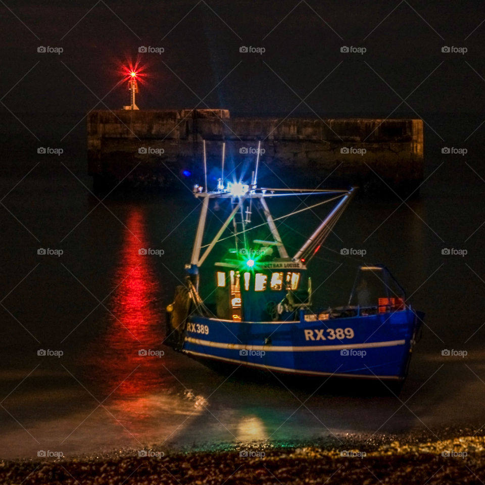 A fishing boat heads off to sea at night from Hastings, UK 