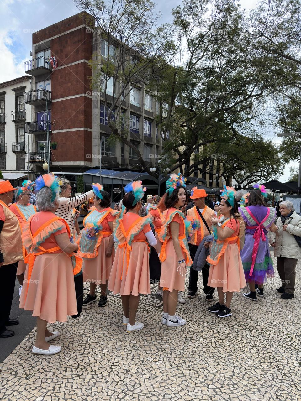 A group of women in bright and colorful costumes getting ready for the start of a parade 