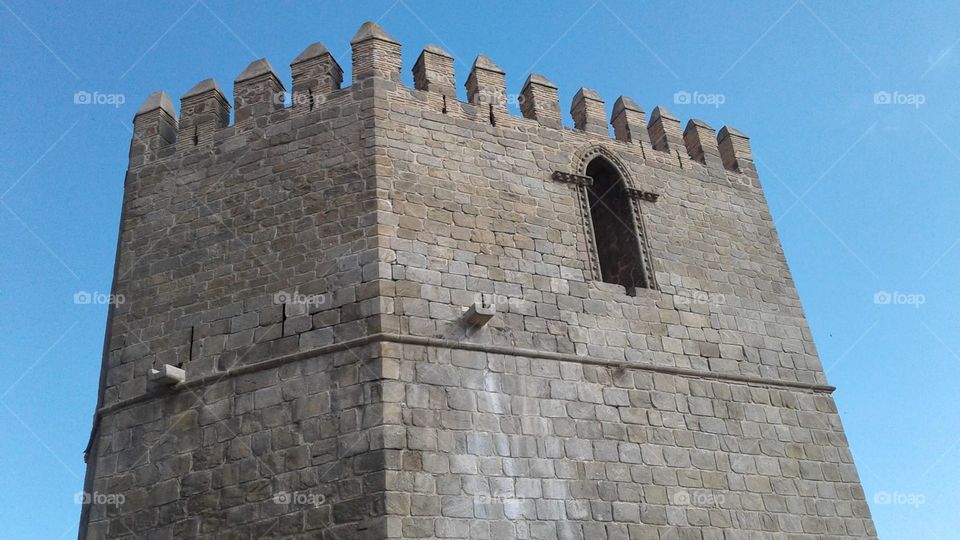 Old stone castle turret with window, against a light blue sky.