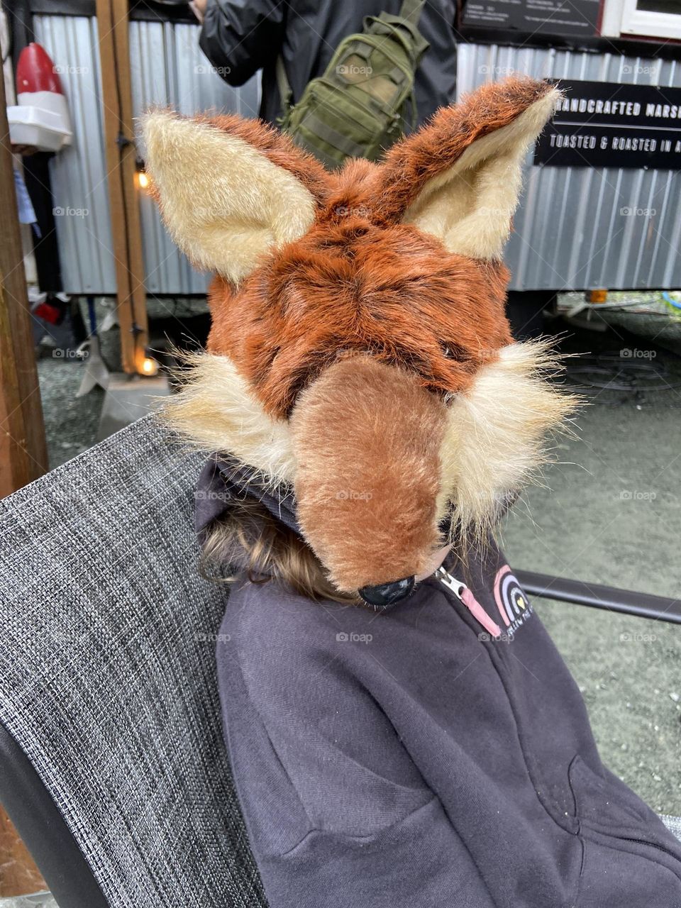 A girl wearing a fluffy plush fox hat at an outdoor restaurant in Juneau, Alaska.