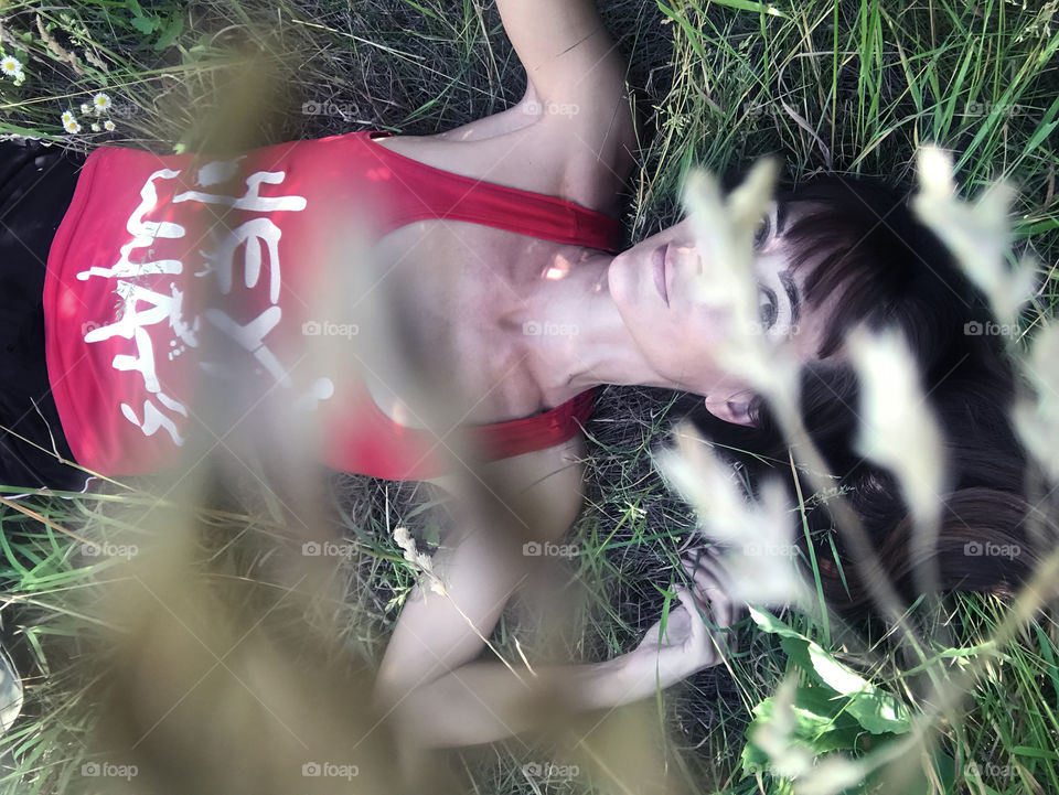 Young woman relaxing in summer green grass in park 