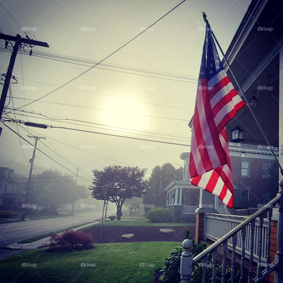 American flag waving in the shadowy morning fog