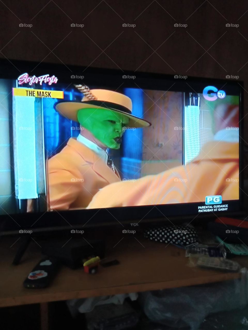 WATCHING MOVIE, THE LEADING MAN WEARING A GREEN MASK WITH HAT ON , IN THE MIRROR