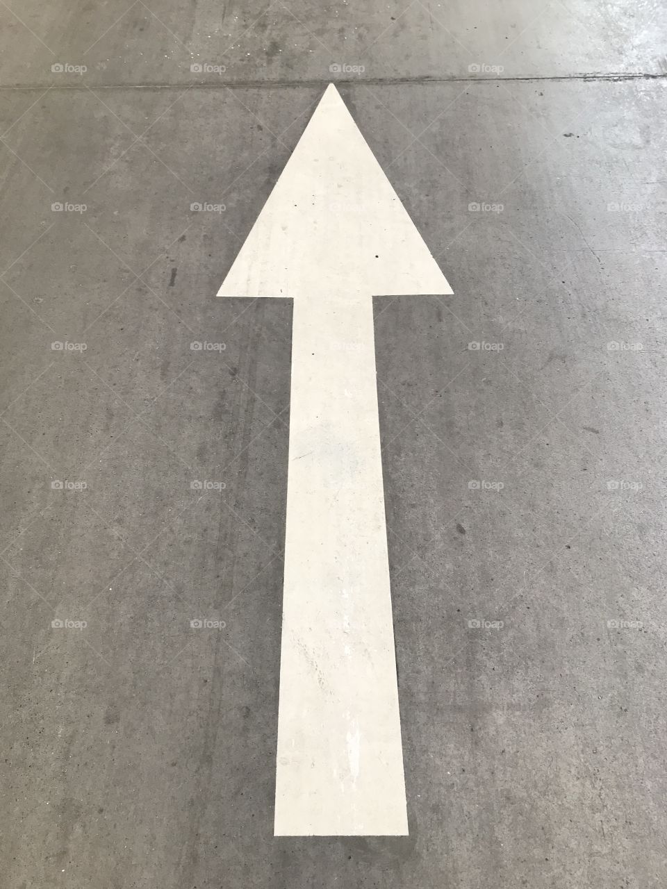 Urban parking lot white arrow signal over asphalt or concrete roadway