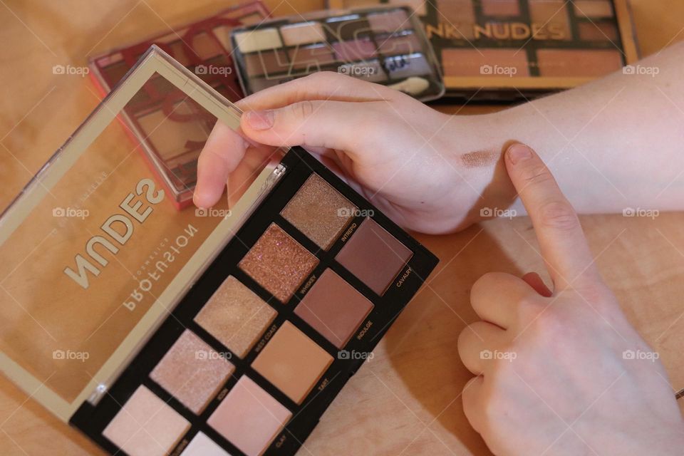 Hand applying eyeshadow color to wrist to see how tone looks against skin