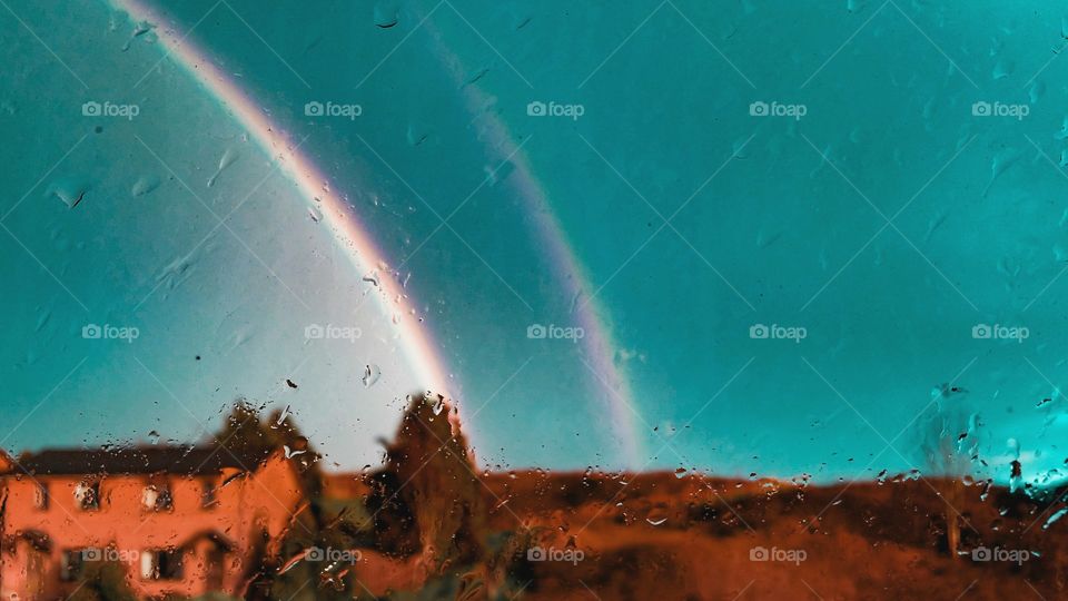 Double rainbow in a turquoise sky and raindrops