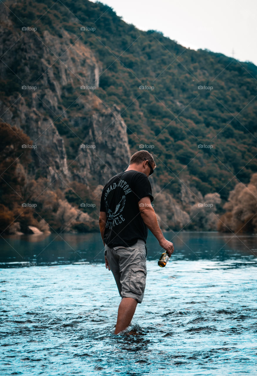 Man in the lake having a beer.