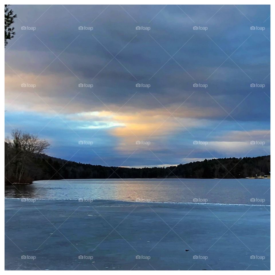 Sun setting over half frozen Lake in Massachusetts. Amazing blend of colors and touch of cold.
