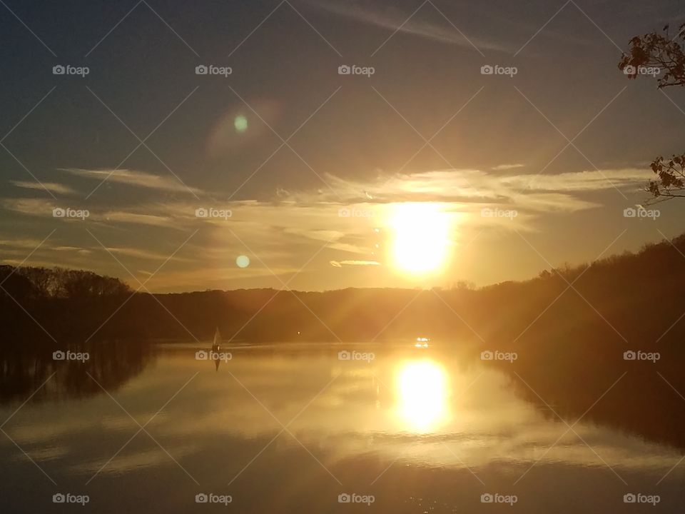 Sun reflected in the water and a sailboat