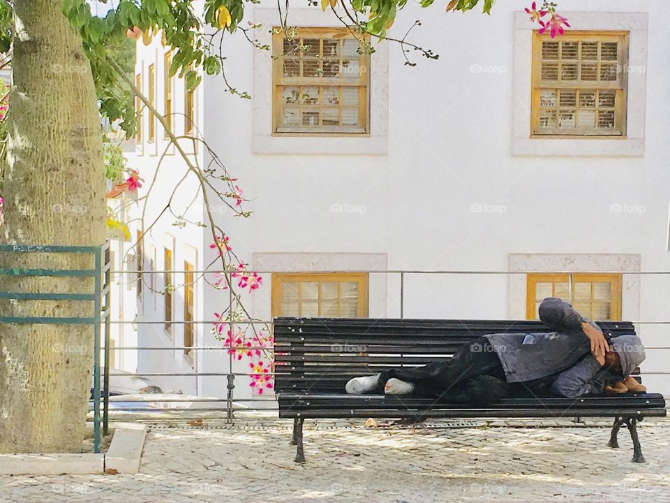Homeless sleeping on the garden’s bench 
