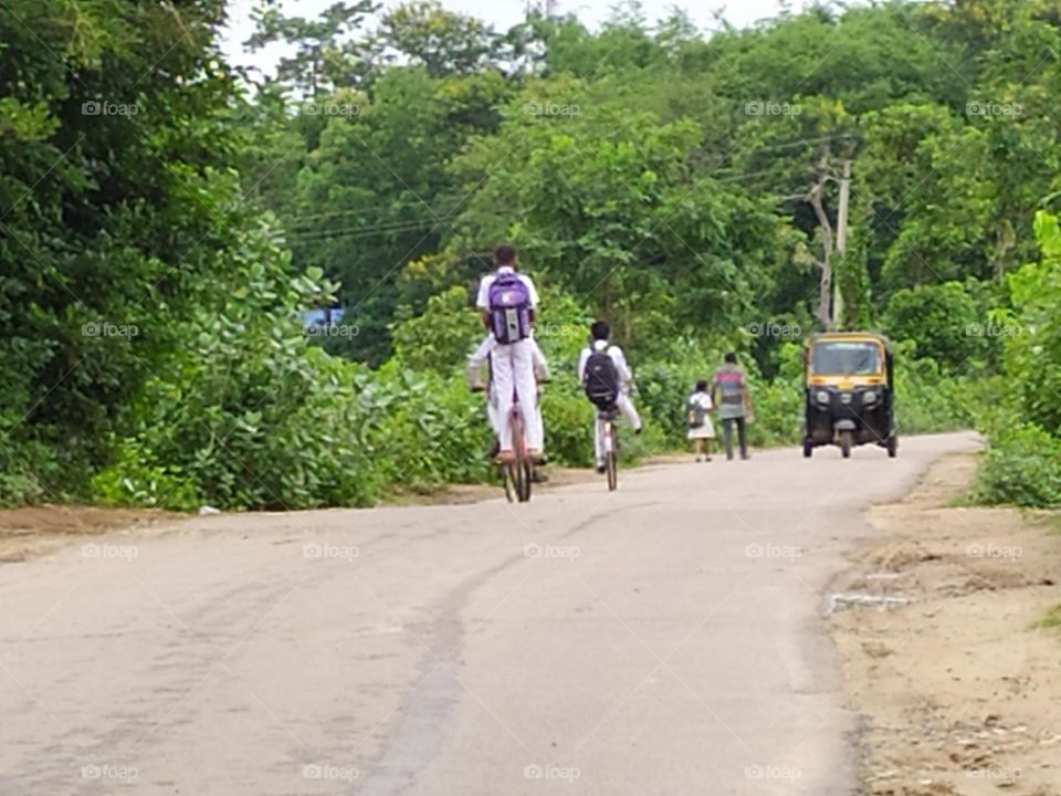 school students back to home riding bicycle on the road