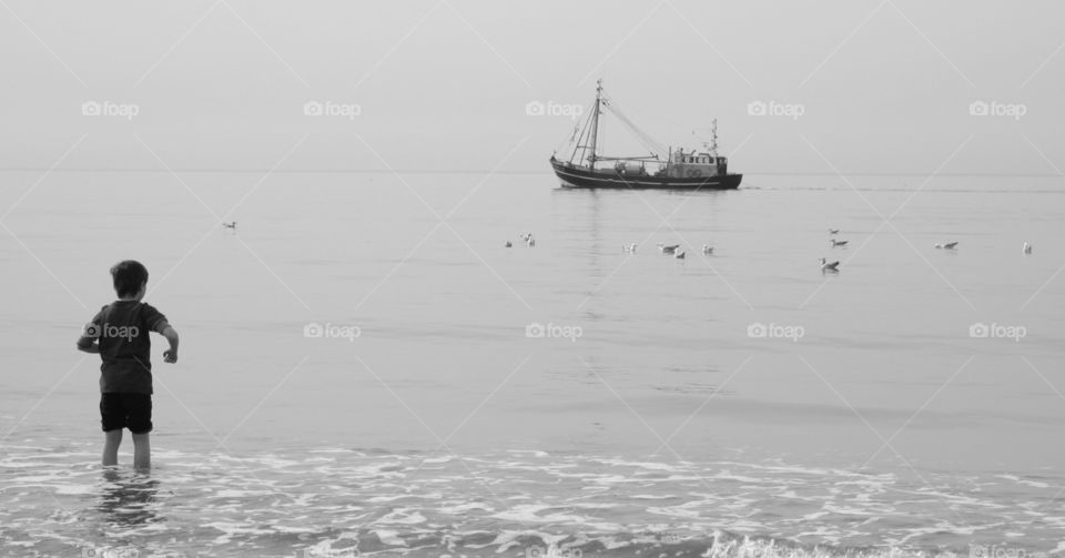 A child watching a fisher boat at sea