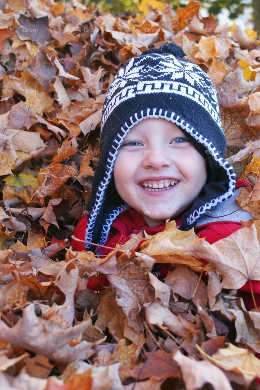 Close-up of a boy in autumn leaves