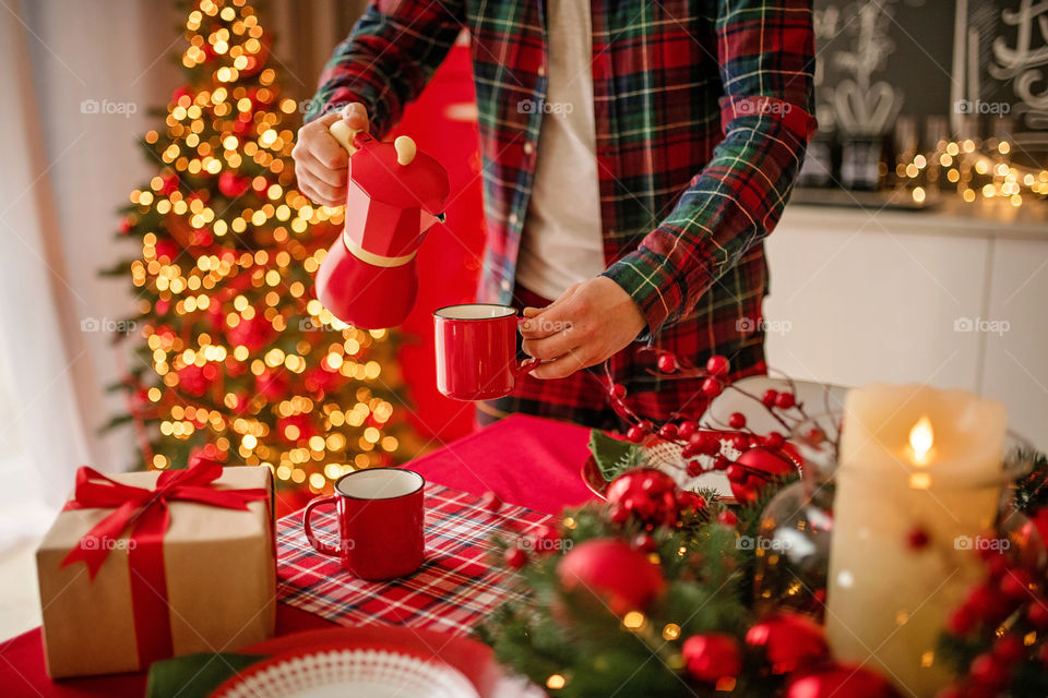 Festive winter cozy kitchen interior with garlands, decorations and gifts.  Christmas dinner at the decorated table.