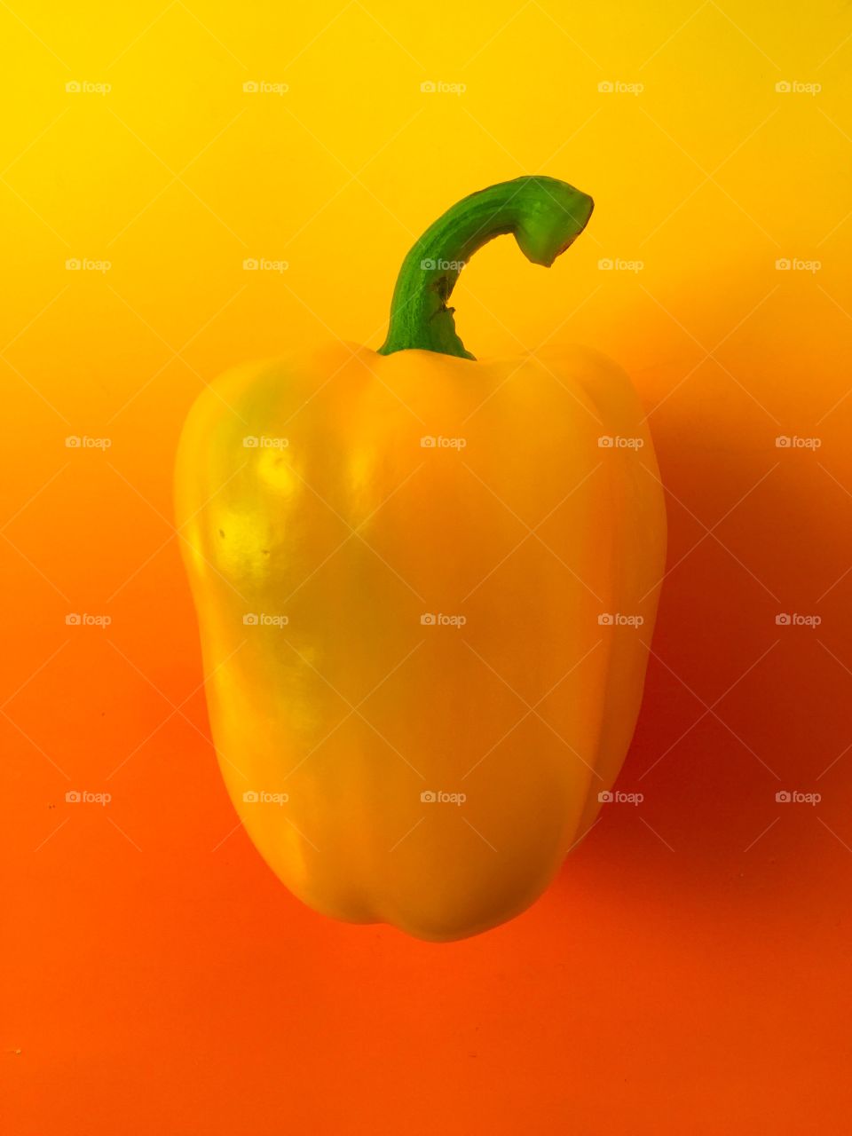 Yellow bell pepper on orange-colored background