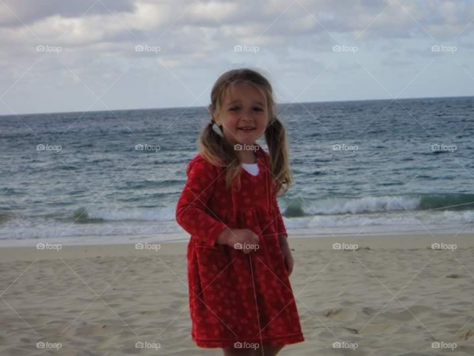little girl 4 years old,  in a red dress on the beach , 
in Cornwall
carvis bay,