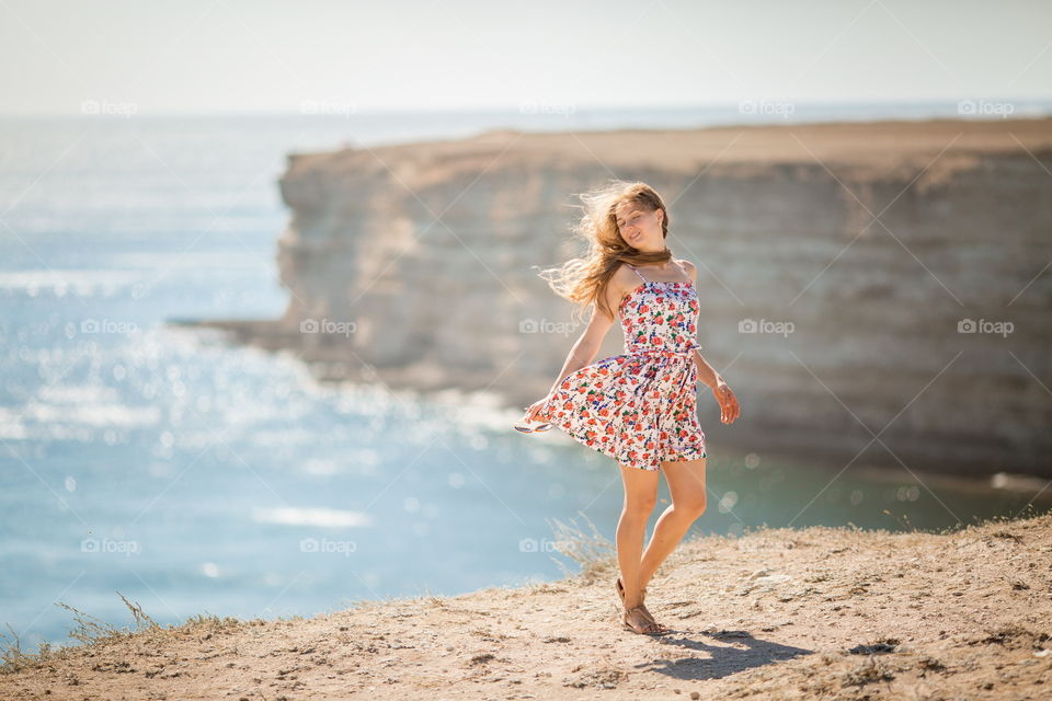 Portrait of beautiful young woman near the sea at sunset