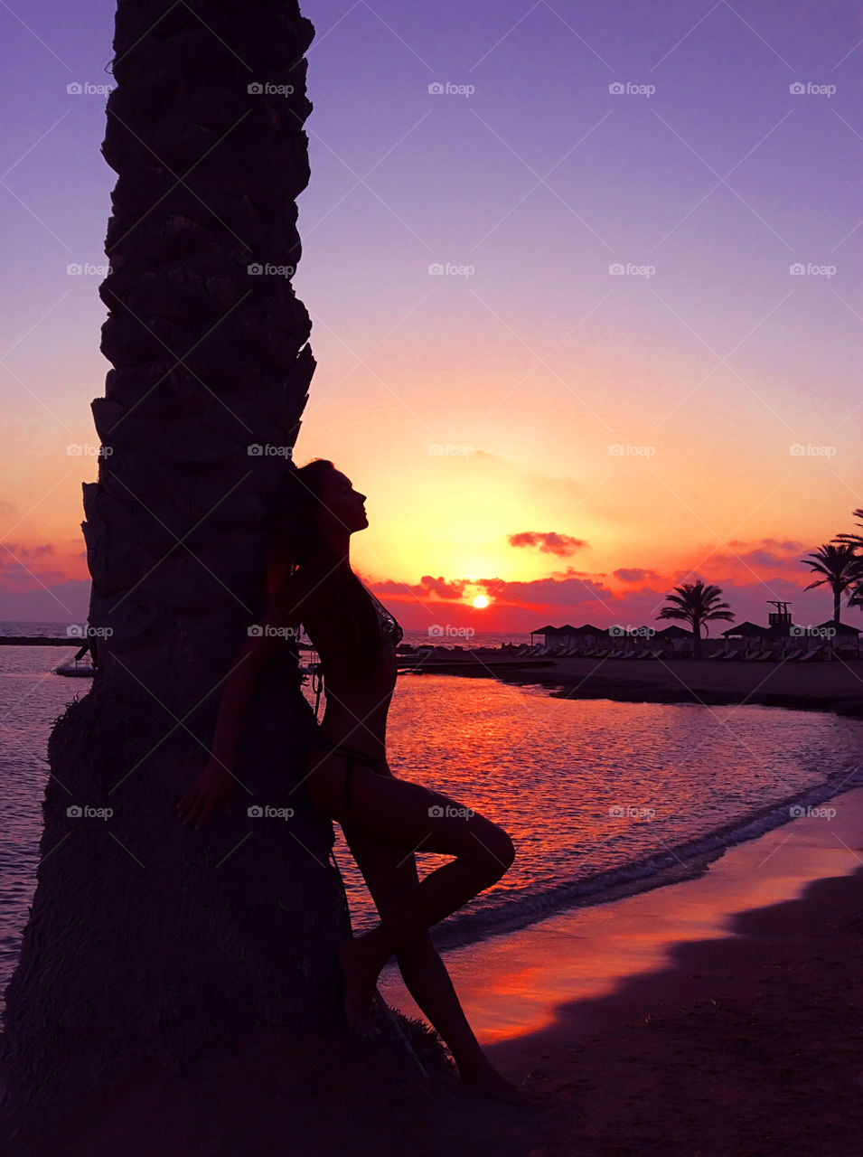 Silhouette of a young woman enjoying her summer tropical vacation at the seaside in the evening 