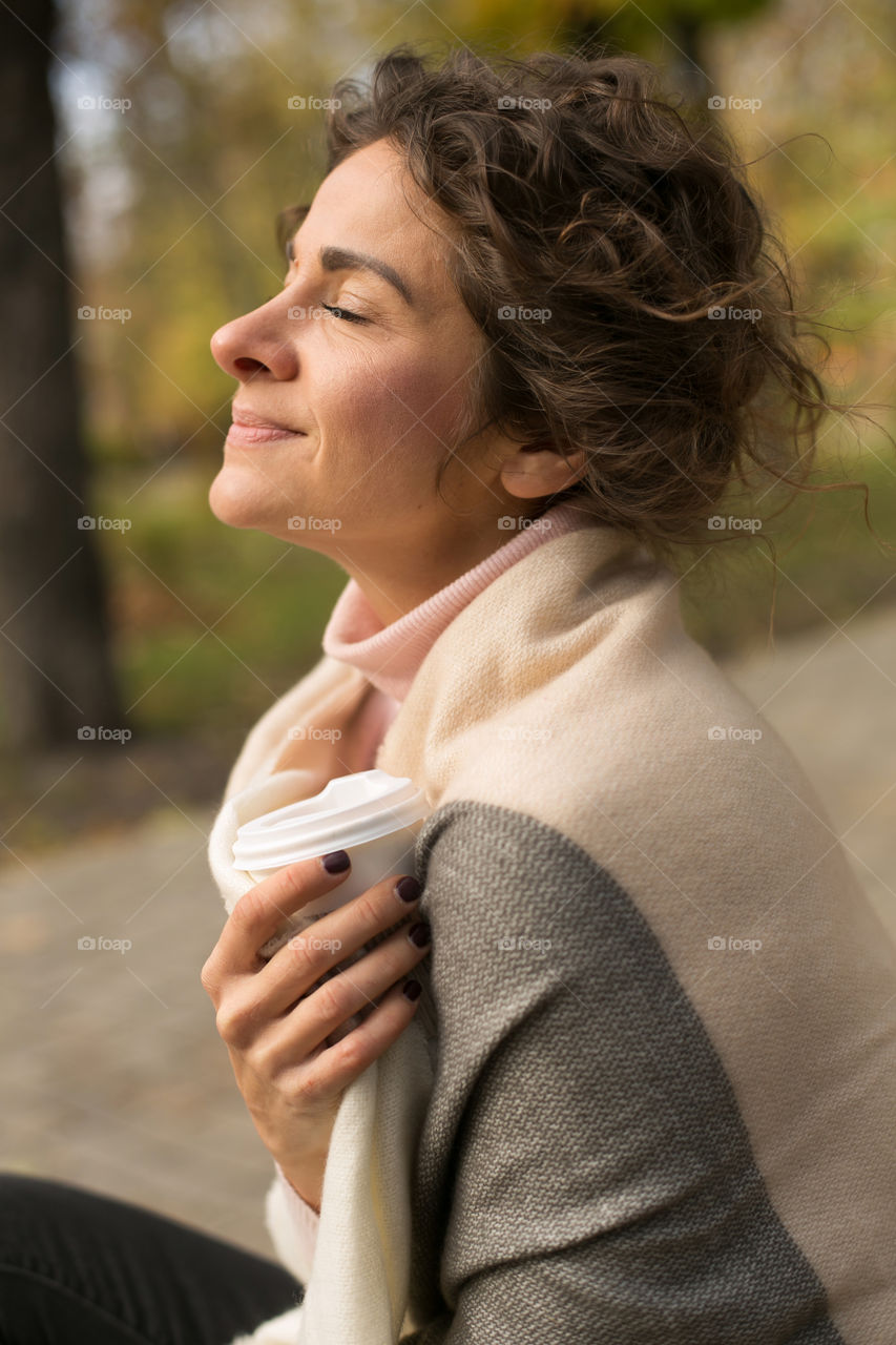 a beautiful girl, during quarantine, sits at the of the park, meditates and thinks about good things. social distance