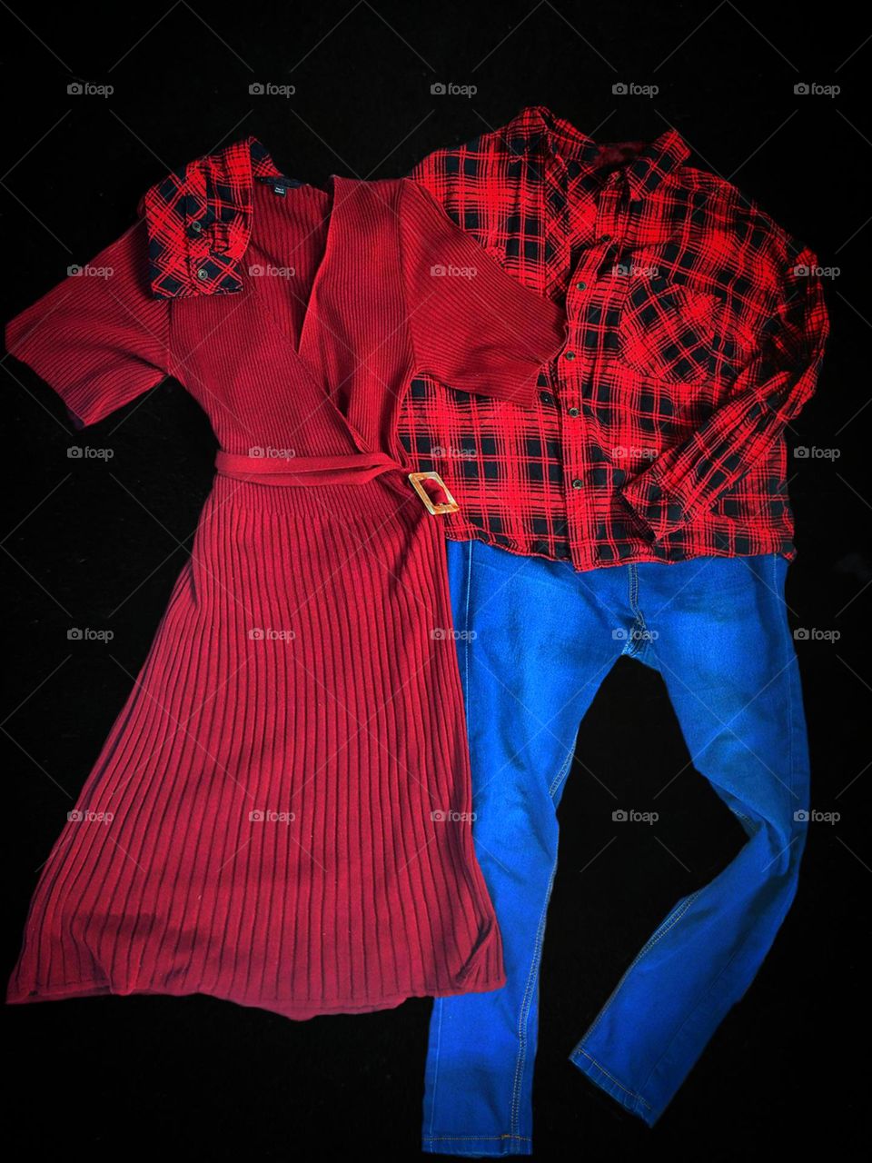 Imitation of human figures with the help of clothes. Red female dress - female figure and male figure in the form of a red checkered shirt and blue jeans. Shirt sleeve on the shoulder of the dress. Emotions of people through clothes. Black background