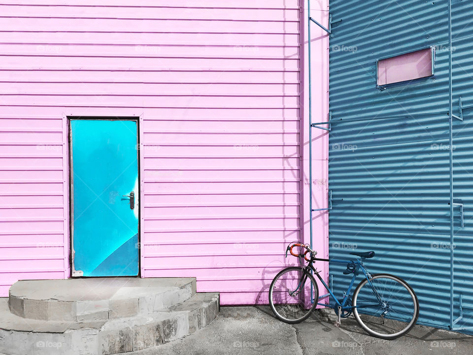 Bicycle standing in front of a pink and blue colorful wall